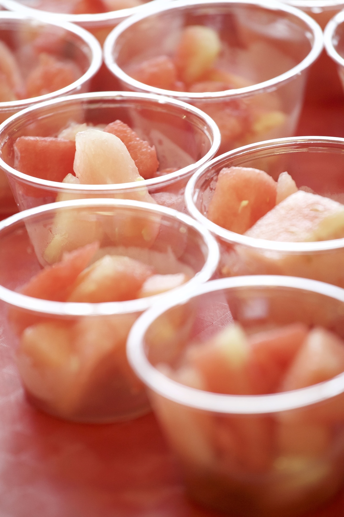 Melon cubes in plastic pots on a tray